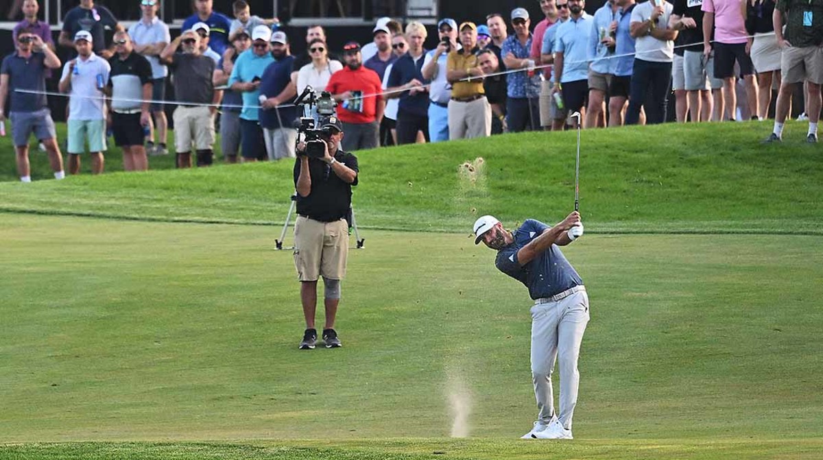 Dustin Johnson is pictured hitting a shot in front of a TV camera at the 2022 LIV Golf Invitational Chicago.
